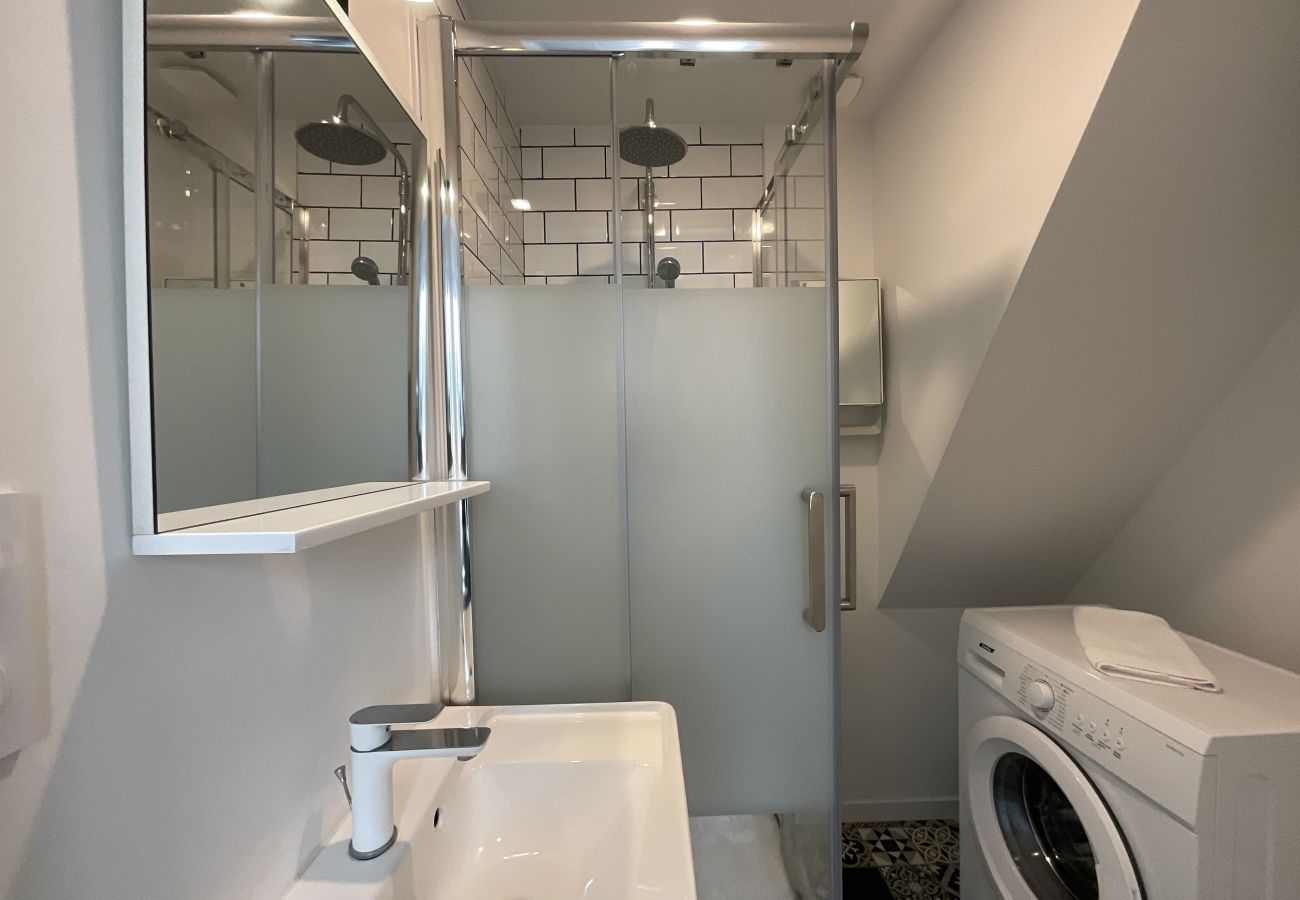 Bathroom with shower, vanity unit and washing machine. 